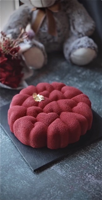 Decadent strawberry mousse cake with a vibrant red hue, with velvet spray.